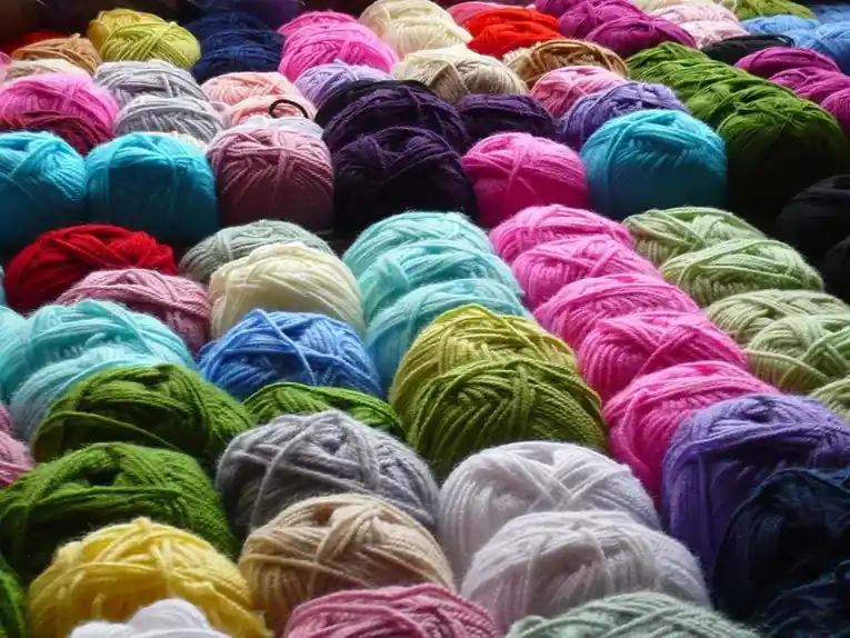 Dozens of wool skeins heaped together in greens, blues, pinks and creams